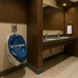 Bathroom stall with a blue 'Out of Order' sign on a urinal.